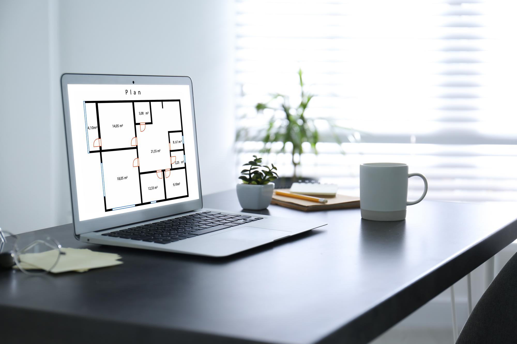Birou imobiliar modern cu planuri și laptop